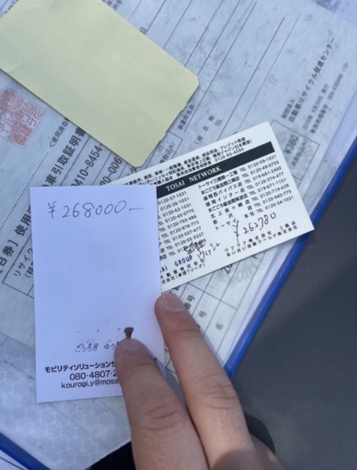 実際の名刺じゃんけん査定の現場写真。業者が名刺の裏に手書きで査定金額を記入した瞬間
